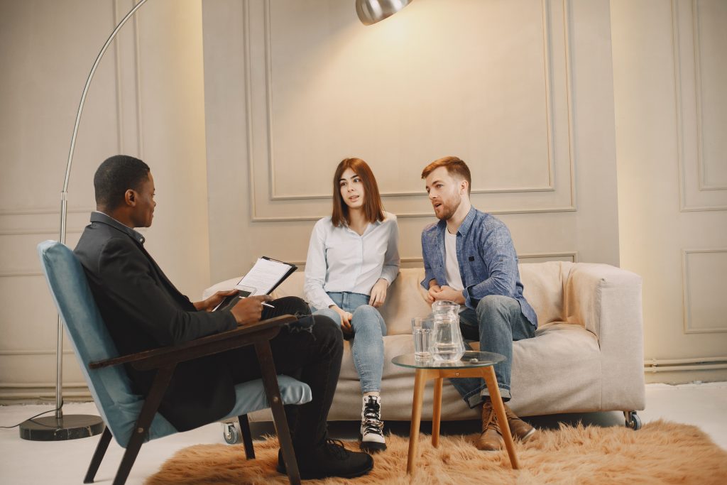 A realtor meeting with a couple to discuss real estate options. Modern indoor setting with a casual atmosphere.