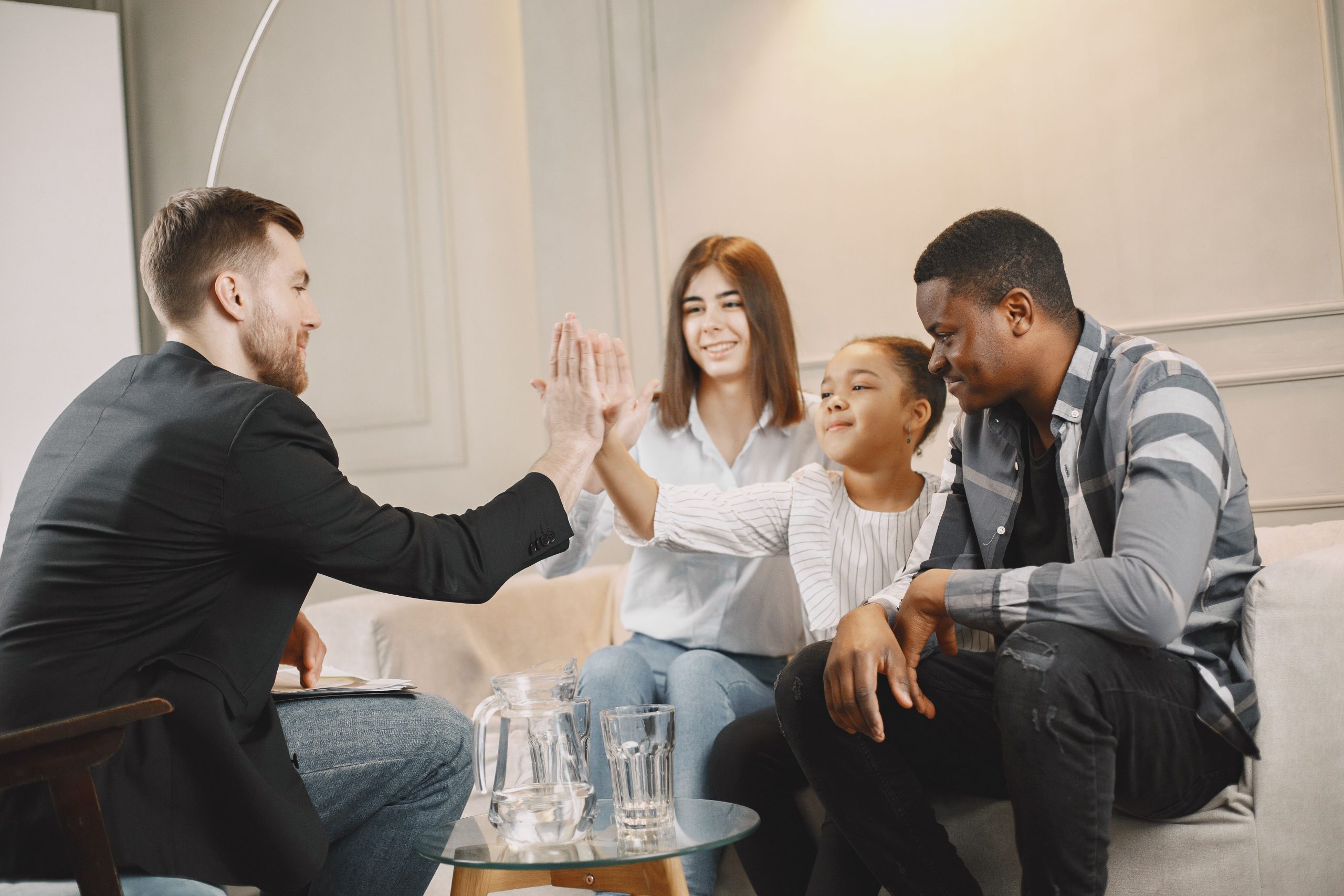 Family joyfully high-fiving while sitting on a sofa indoors, promoting teamwork and unity.